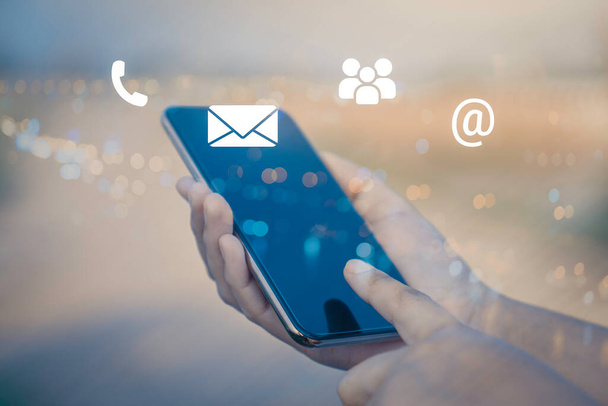 Skontaktuj się z nami lub Customer support hotline people connect. Biznesmen korzystający z telefonu komórkowego z ikonami (e-mail, telefon, poczta). - Zdjęcie, obraz