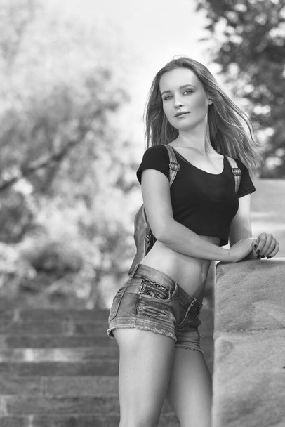 Young blond girl, in short shorts standing on the stairs - 写真・画像