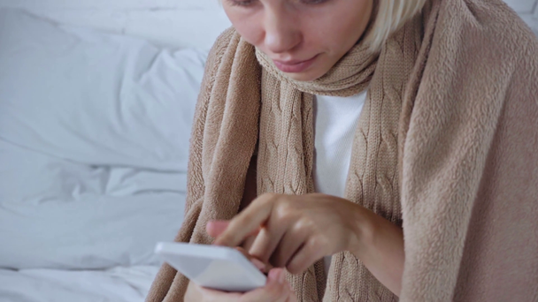 przycięty widok chorej kobiety za pomocą smartfona i kaszel w domu - Materiał filmowy, wideo