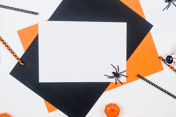 Halloween party composition on paper background in black, orange and white. Flat lay, Halloween party decor - drink straws, pumpkins, bats and spiders. Mock-up, greeting card, flat lay, top view. - Фото, зображення