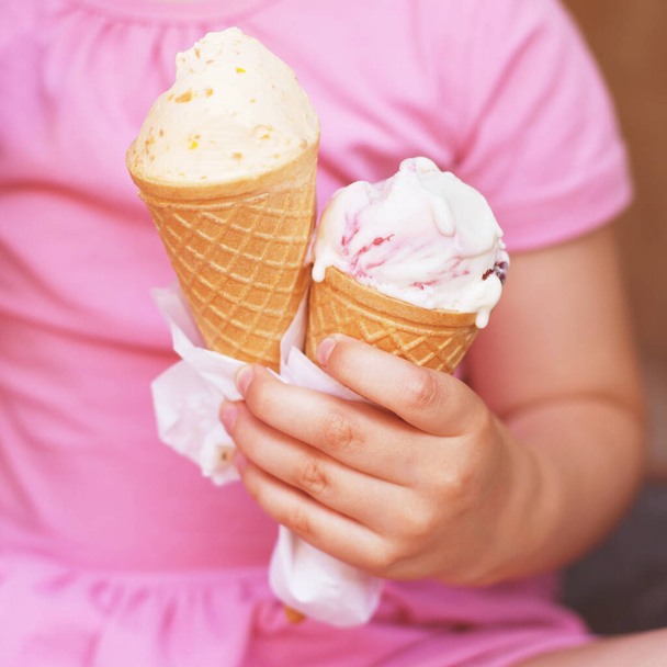 girl in pink dress eating ice cream in hot weather - 写真・画像