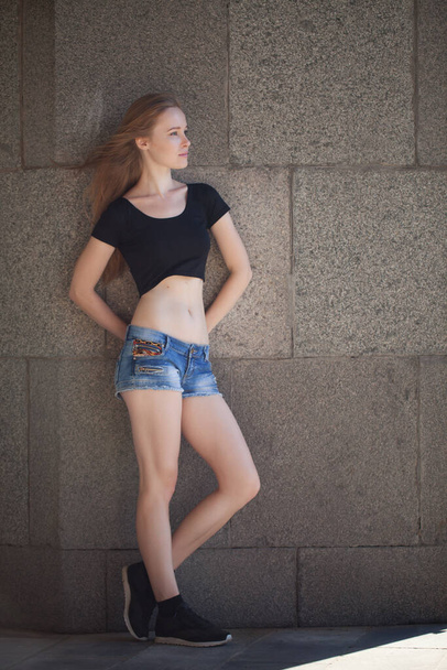 a young girl in shorts and a black topic in the city. bright emotions, style life, sunny day - Fotoğraf, Görsel