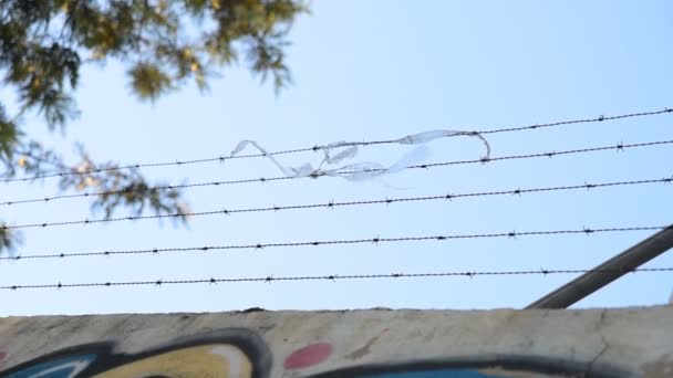 Some debris flutters caught in the barbed fence of a protected wall - Footage, Video