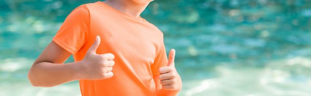 cropped view of boy in orange t-shirt showing thumbs up, website header - 写真・画像