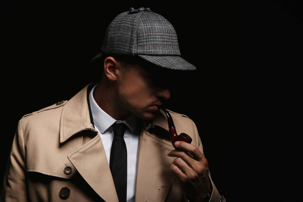 Old fashioned detective with smoking pipe on dark background - Foto, Bild