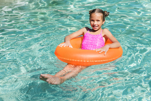 dziewczyna patrząc w kamerę podczas pływania na nadmuchiwanym pierścieniu w basenie - Zdjęcie, obraz