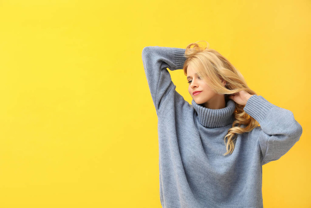 Beautiful young woman wearing warm blue sweater on yellow background. Space for text - Photo, Image