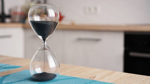 Closeup of hourglass with defocus kitchen on background. Concept of time to cook - Photo, image