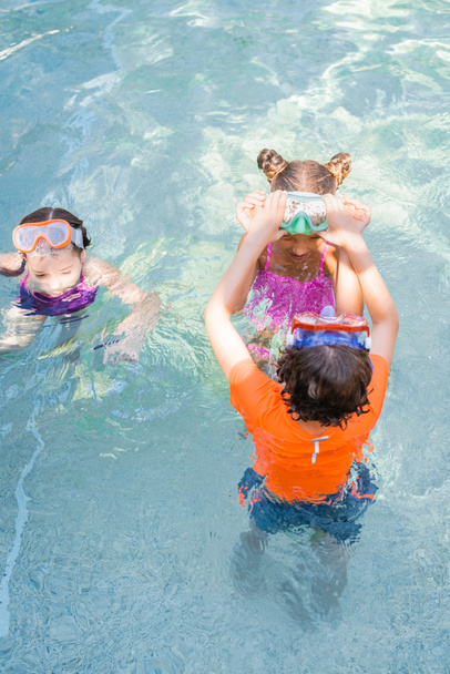 vista de ángulo alto de los amigos dando cinco altos mientras se divierten en la piscina - Foto, imagen