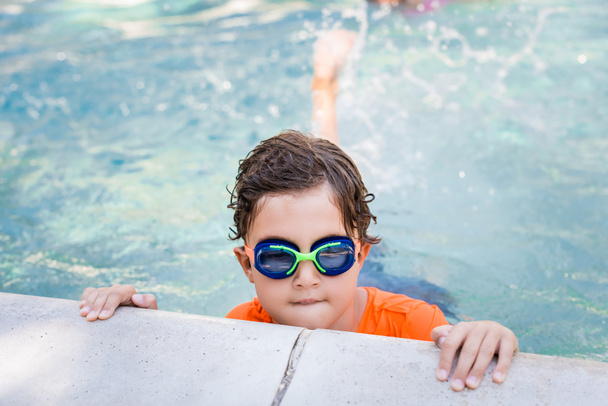 niño con gafas de baño en el agua cerca de la piscina - Foto, Imagen