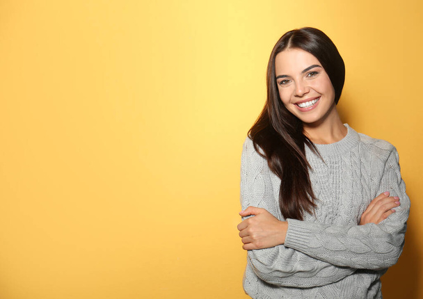 Happy young woman wearing warm sweater on yellow background. Space for text - Photo, Image