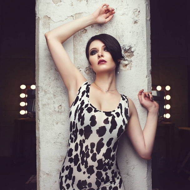 girl posing in white skin-tight leopard dress in studio - Photo, Image