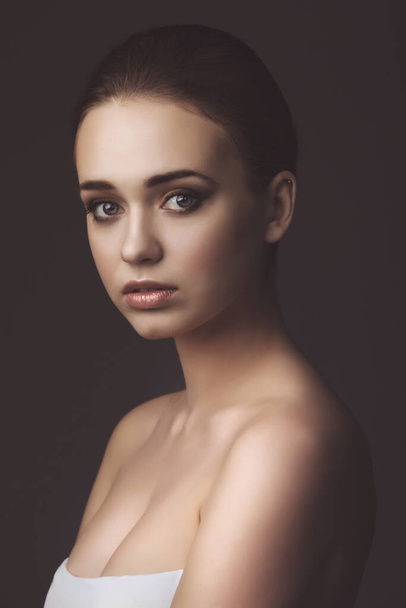 studio portrait of young beautiful girl on dark background - Fotó, kép