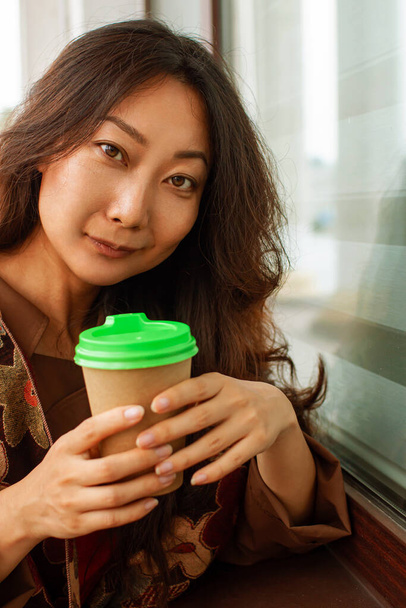 Hymyilevä aasialainen liike nainen, jolla on kahvitauko lähellä toimistoa  - Valokuva, kuva