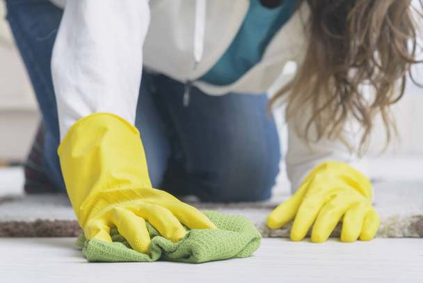 жінка в жовтих гумових рукавичках протирає пил на підлозі вдома
 - Фото, зображення
