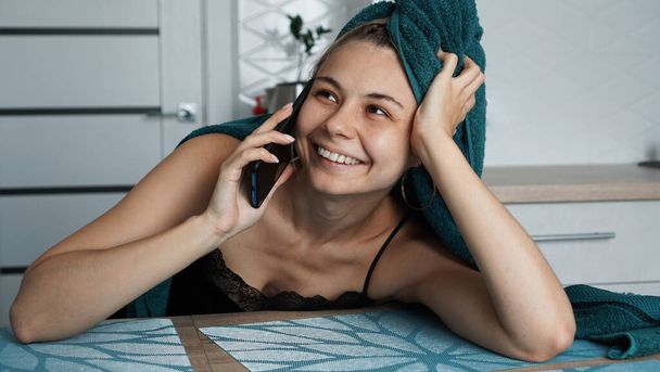 Young woman in kitchen. Talking on phone and smile - Photo, image