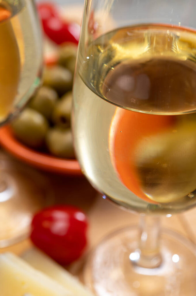 Ποτήρια από ξηρό κρύο κρασί σέρι φίνο σερβίρεται με ισπανικά τάπας, τυρί manchego, πράσινες ελιές, κρακεράκια τυρί - Φωτογραφία, εικόνα