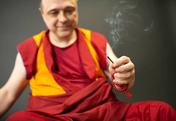 Moine bouddhiste tenant un bâton d'encens fumant dans sa main - Photo, image