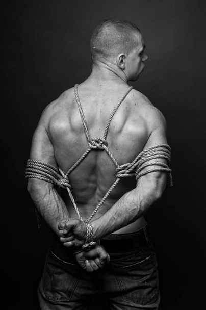 Мускулистый мужчина-модель, завязанная в традиционном японском шибари - Фото, изображение
