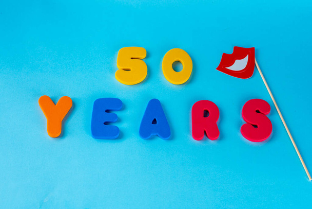 50 years old celebrating classic logo. Colored happy anniversary 50 th colored numbers on blue background. Greetings celebrates card. Traditional digits of ages. Top view. - Photo, Image