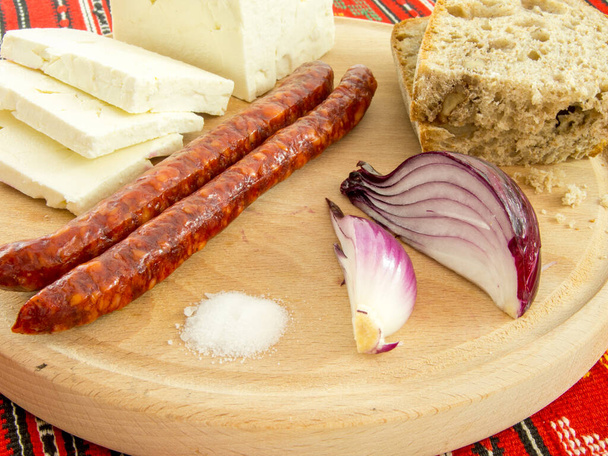 spuntino tradizionale rumeno di salsicce di cipolla al formaggio e pane su un piatto di legno - Foto, immagini