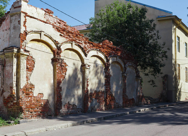 Zniszczony starożytny dom z łukami i kolumnami na ulicy Vyborg, rozpadający się murowany budynek w stylu europejskim w słoneczny dzień - Zdjęcie, obraz