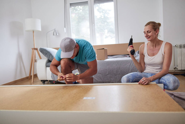 Husband and wife assembling new furniture - renovation home concept. - 写真・画像