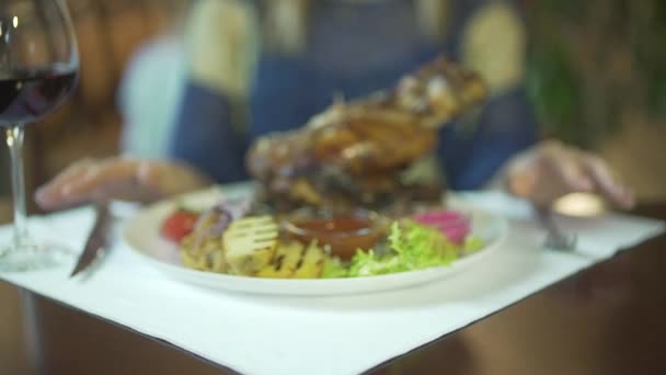Close-up vista sobre enorme pedaço grelhado de carne na placa vegetal mulheres mãos batendo dedos na mesa esperando para comer - Filmagem, Vídeo
