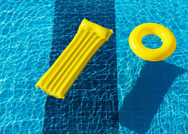 anello galleggiante e materasso sull'acqua blu della piscina - Foto, immagini