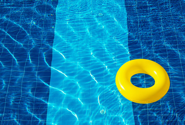 Galleggiante piscina gialla, anello galleggiante in una rinfrescante piscina blu - Foto, immagini