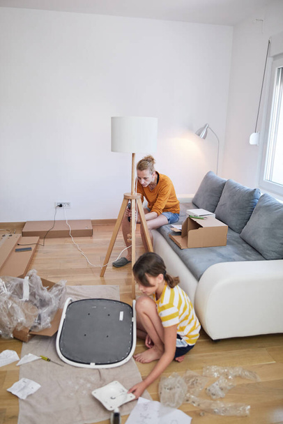 Mother and daughter assembling furniture in new apartment, moving in and being hardworking. - Valokuva, kuva