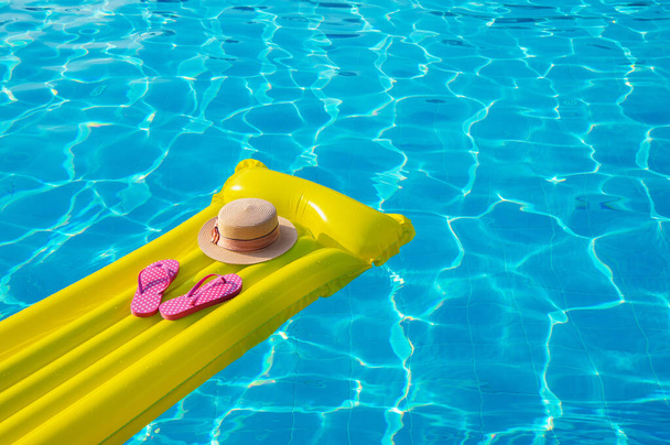 Tengerparti nyaralás háttér. Felfújható matrac, papucs és kalap úszómedencében. - Fotó, kép