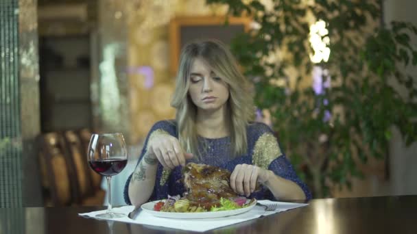 Joven hermosa chica rubia tatuada en la cena de lujo restaurante rasgando carne comiendo con los dedos comportamiento inapropiado - Metraje, vídeo