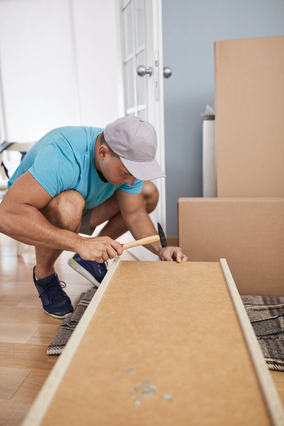 Homme assemblant des meubles dans un nouvel appartement, emménageant et travaillant dur. - Photo, image