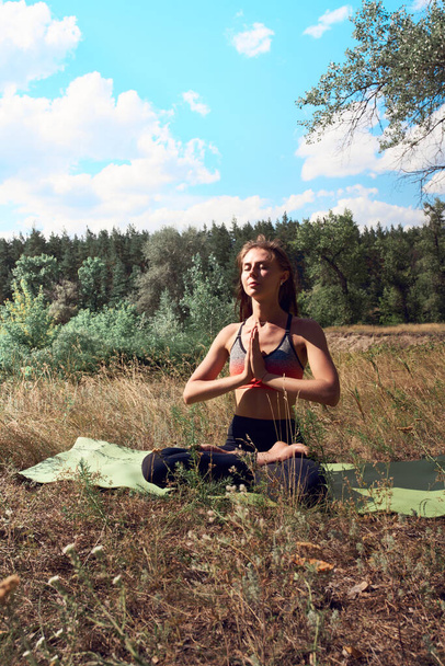 Beautiful young woman meditating in the morning on the nature. - Photo, Image