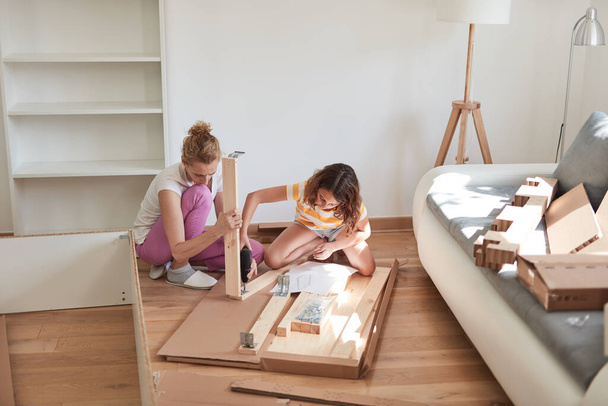Mother and daughter assembling furniture in new apartment, moving in and being hardworking. - Photo, Image