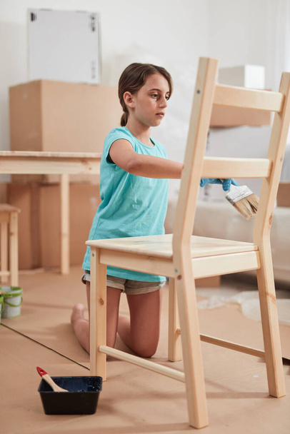 Pieni tyttö maalaus ja kokoaminen huonekalut uudessa asunnossa, liikkuvat ja ovat ahkeria. - Valokuva, kuva