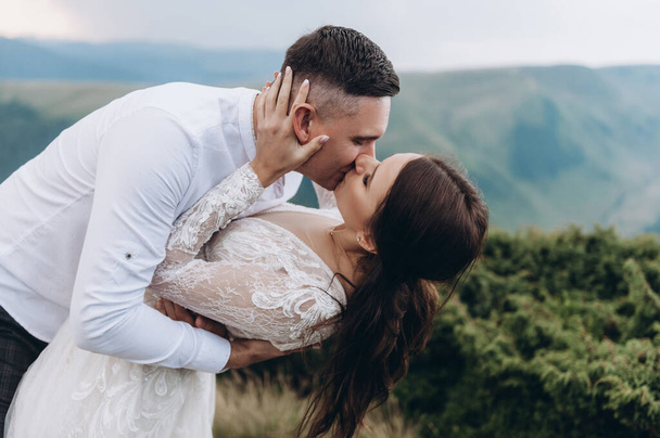 Wedding, Beautiful Romantic Bride and Groom Kissing and Embracing in the mountans - Fotografie, Obrázek