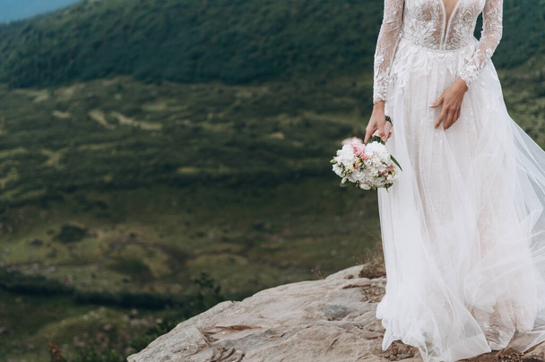 букет непроданных. Невеста в белом платье в горах - Фото, изображение