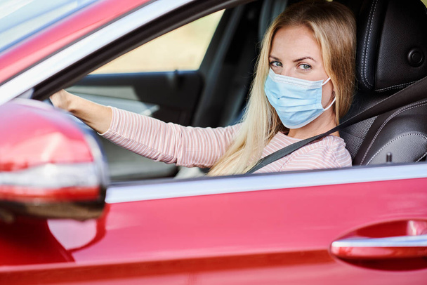 Mujer con una máscara protectora conduciendo un coche                                - Foto, Imagen