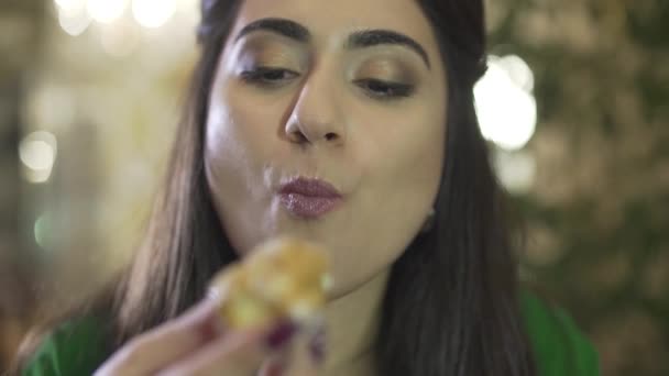 jong brunet vrouw genieten van eten vla gebak dessert met vuile handen likken vingers in restaurant in close-up - Video