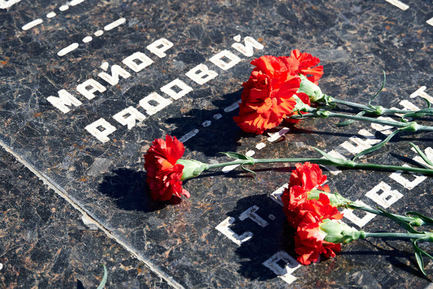 bloemen ter nagedachtenis aan gesneuvelde soldaten, rode anjers op zwart marmer, Russische tekst van soldaten militaire rang - sergeant, majoor, kolonel, luitenant-kolonel, soldaat, korporaal - Foto, afbeelding
