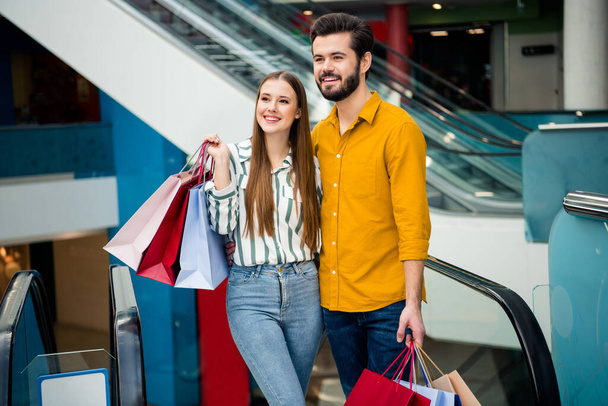 Portrait of charming positive comfort cozy students two people spouses move staircase hold packages hug embrace enjoy free time relax weekend in shopping mall center store - Foto, imagen