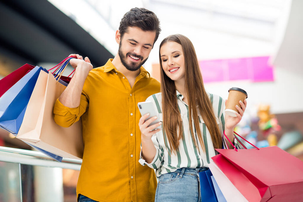 Portrait of two people man woman have break pause use smartphone check boutique retail off-sales notification hold coffee take-away cup many packages in shopping mall aisle - Foto, immagini
