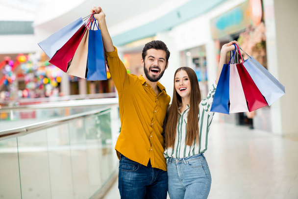 Portrait of his he her she nice attractive lovely satisfied glad cheerful cheery couple having fun celebrating carrying new things clothes trade brandy bargain indoors - Фото, изображение