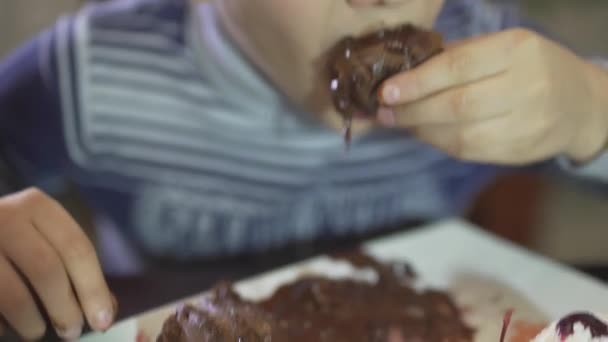 Крупним планом вид на милий маленький хлопчик їсть шоколадний десерт з брудними руками брудний рот огидно їсть роблячи безлад
 - Кадри, відео