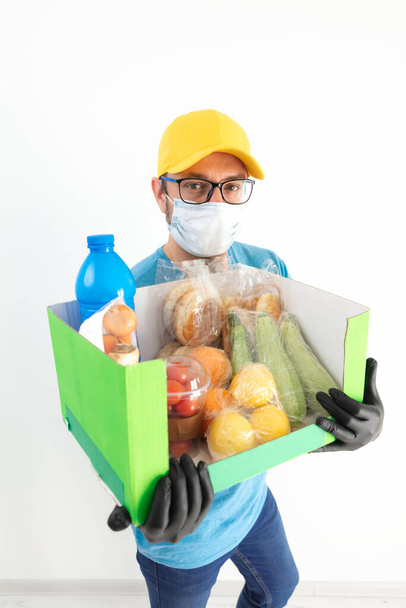 食料品と保護マスク保持ボックスを持つ配達人. - 写真・画像