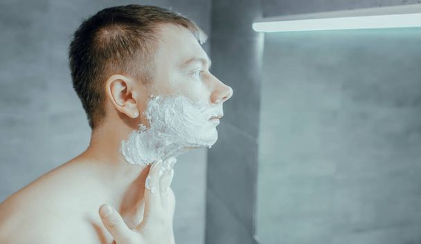 Guy puts shaving gel on his face - Photo, Image