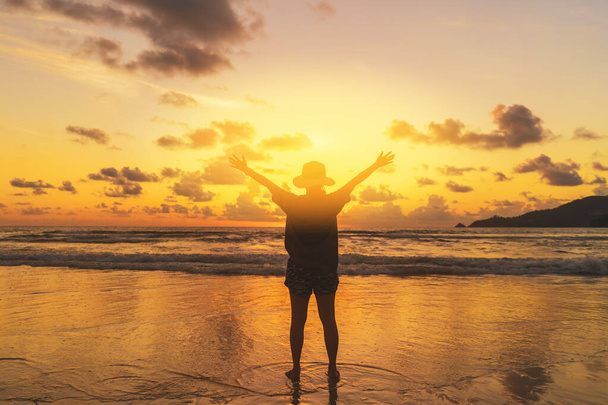 Donna felice alzare la mano sulla spiaggia tropicale con sfondo cielo tramonto. Vacanza di viaggio e la libertà si sentono bene concetto. Vintage tono effetto filtro colore stile. - Foto, immagini
