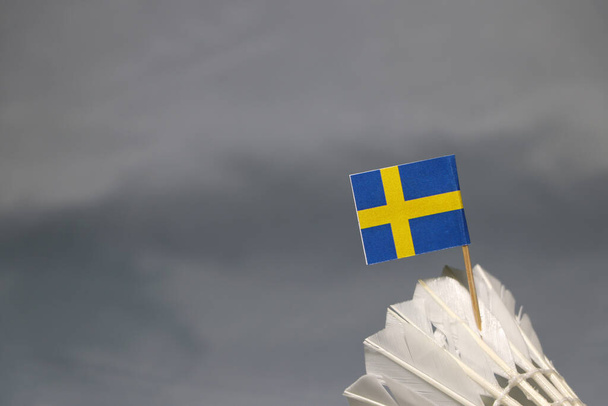 Mini Sweden σημαία κολλήσει στο λευκό shuttlecock με γκρι φόντο. Έννοια του badminton αθλητισμού.  - Φωτογραφία, εικόνα